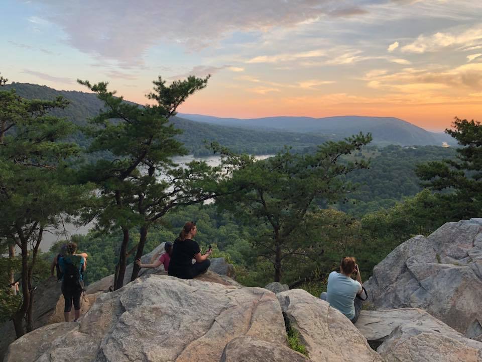 hikers sitting on Weverton Cliffs boulders at sunset